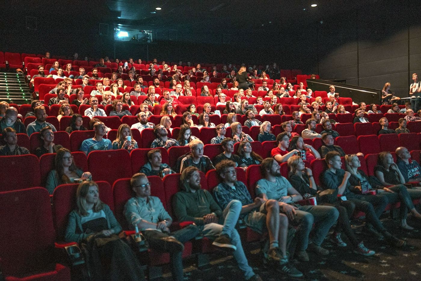 Rows of empty red cinema seats either side of a lit aisle.